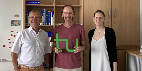 Prof. Dr. Hartmut Holzmüller, Gastforscher Prof. Philip J. Rosenberger III mit TU Logo und Karen Wesely (von links nach rechts)