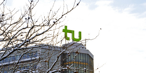 A building with TU Dortmund logo and branches covered with snow.