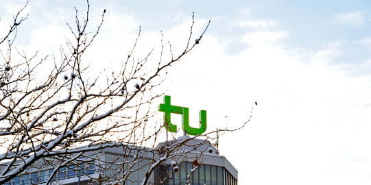 A building with TU Dortmund logo and branches covered with snow.